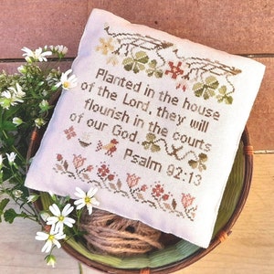 May include: White fabric with green and brown embroidery of shamrocks and vines. The fabric has a quote from Psalm 92:13, "Planted in the house of the Lord, they will flourish in the courts of our God."