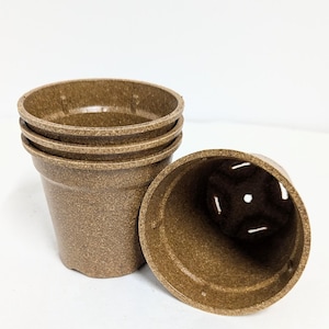May include: Four brown biodegradable plant pots stacked on top of each other. The pots have drainage holes in the bottom.