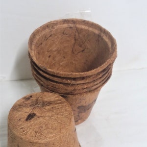 May include: A stack of brown biodegradable pots made from coconut fiber. The pots are stacked on top of each other and are ready to be used for planting.