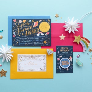 May include: A selection of stationery items, including a blue card with "Super Human Award" text, a yellow envelope, a pink envelope, and a "Super Human Patch". Decorative stars and gems are scattered around the items.