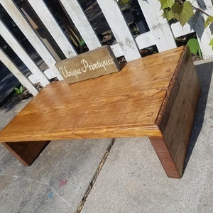Puede incluir: Una mesa de caf&eacute; de madera r&uacute;stica con un acabado de madera natural. La mesa tiene una tapa rectangular y dos patas largas rectangulares. La mesa est&aacute; sentada sobre una superficie de concreto. El texto "Unique Primitives" es visible en un peque&ntilde;o letrero de madera.