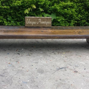 Puede incluir: Una mesa de caf&eacute; de madera marr&oacute;n oscuro con un dise&ntilde;o &uacute;nico. La mesa tiene una tapa rectangular y una base curva. La mesa est&aacute; sentada sobre una superficie de concreto. El texto "Unique Primtiques" es visible en un peque&ntilde;o bloque de madera.