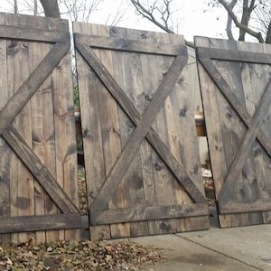 May include: Three rustic wooden barn doors with a dark brown stain and an X-shaped design. The doors are made of reclaimed wood and have a weathered look.