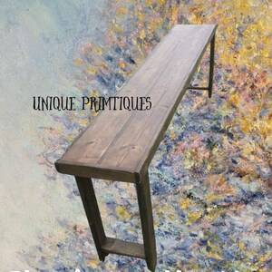 May include: A rustic wooden console table with a dark brown stain and black metal legs. The table is 72 inches long and 12 inches wide. The table is on a colorful background.