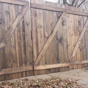 May include: A set of three rustic wooden barn doors with a diagonal wood plank design. The doors are made of weathered wood with a dark brown stain.