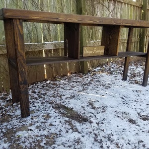 May include: A rustic wooden console table with three shelves and a distressed brown finish. The table is standing on a snowy ground with a sign that reads "Unique Finds".