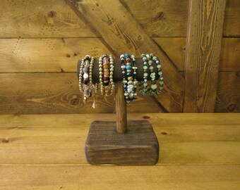 May include: A wooden jewelry stand with a square base and a round post, displaying a variety of colorful beaded bracelets.