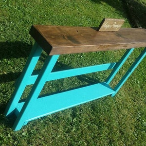 May include: A turquoise blue console table with a wooden top. The table has a shelf and a sign that says "Always Adventure".
