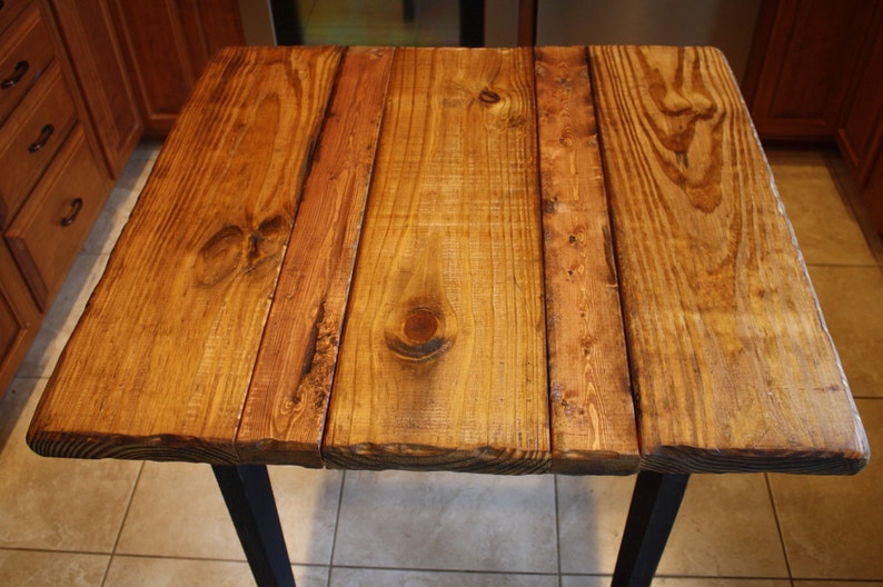 Puede incluir: Una tapa de mesa de madera r&uacute;stica con un acabado de madera natural. La tapa de mesa est&aacute; hecha de varias tablas de madera que se han unido. La madera tiene un color marr&oacute;n miel c&aacute;lido y una textura ligeramente rugosa.