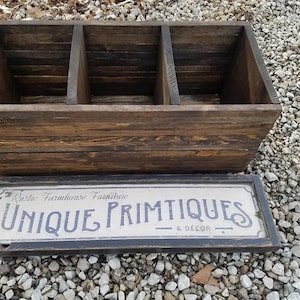 May include: A rustic wooden box with three compartments, stained dark brown. The box has a lid with a sign that reads "Rustic Farmhouse Furniture Unique Primitives & Decor".