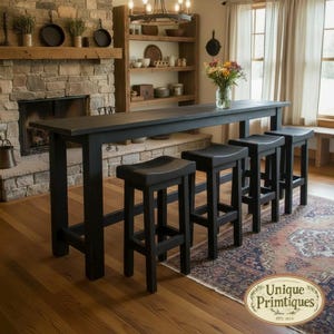 May include: A long, rectangular black wooden bar table with four matching black wooden bar stools. The furniture features a smooth, dark finish and simple, sturdy construction. A logo in the bottom right corner reads Unique Primtiques.