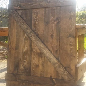 May include: A rustic wooden door with a diagonal brace. The door is made of reclaimed wood and has a dark brown stain.