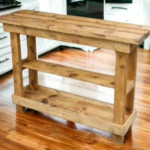 May include: A rustic wooden console table with two shelves. The table is made of natural wood with a light brown finish. It has a simple design with straight lines and a rectangular shape.