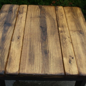 May include: A rustic wooden table top with a dark brown stain. The table top is made of five planks of wood.