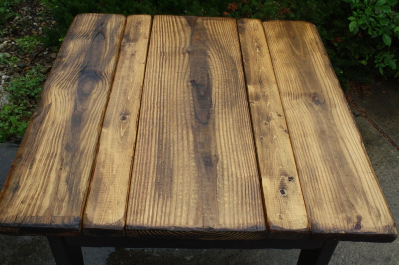 May include: A rustic wooden table top with a dark brown stain. The table top is made of five planks of wood.