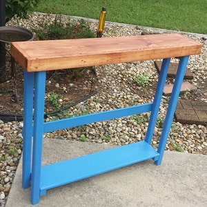 May include: A small wooden table with a blue painted base and a natural wood top. The table has a shelf underneath the top.