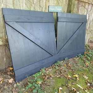 May include: A pair of black wooden barn doors with a diagonal brace and a sign that reads "Unique Antiques".