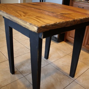 Puede incluir: Una mesa de madera r&uacute;stica con una tapa de madera natural y patas pintadas de negro. La mesa tiene un dise&ntilde;o de borde vivo y es perfecta para una cocina de estilo r&uacute;stico o industrial.