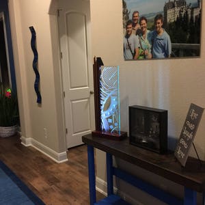 May include: A blue and brown console table with a glass sculpture, a framed photo, and a sign that reads "Live, Laugh, Love".