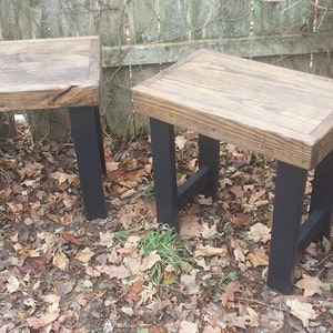 May include: Two wooden end tables with black metal legs. The tables have a rustic, reclaimed wood look and are perfect for a living room or bedroom.