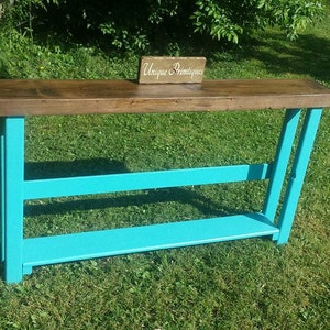 May include: A turquoise console table with a wooden top and a sign that reads "Unique & Primitive".