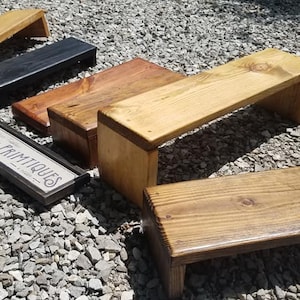 May include: Five wooden shelves of varying sizes and finishes. The shelves are made of natural wood and have a rustic look. The shelves are arranged in a staggered pattern on a gravel surface. A sign with the text "Unique Primitives" is in the foreground.