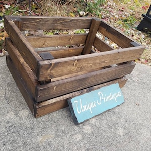 May include: A dark brown wooden crate with a sign that says "Unique Printiques" on it.