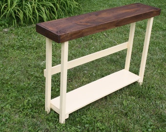 May include: A wooden console table with a dark brown top and a white base. The table has a shelf for storage.