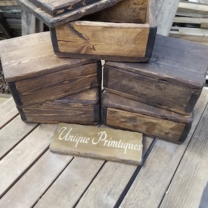 May include: A set of five rustic wooden boxes with lids. The boxes are stacked on top of each other and have a dark brown stain. The boxes are made of reclaimed wood and have a unique, handcrafted look. The boxes are perfect for storing small items or for use as decorative accents.