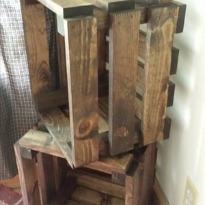 May include: Three wooden crates stacked on top of each other. The crates are made of dark brown wood and have a rustic appearance.