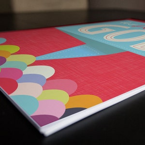 K&ouml;nnte beinhalten: Ein rotes Notizbuch mit einem blauen und wei&szlig;en Banner, auf dem "The Go-To Guide" steht. Der Einband zeigt ein farbenfrohes Design aus &uuml;berlappenden Kreisen in den Farben Rosa, Gelb, Gr&uuml;n, Blau und Lila.