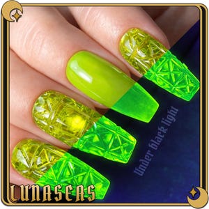 May include: Long fingernails featuring a vibrant neon yellow polish with a textured, geometric, diamond-cut pattern on the tips. The nails exhibit a bright, glowing effect under black light, with the text "Under black light" and "LUNASEAS" visible.