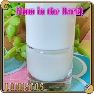Puede incluir: Un frasco de vidrio transparente lleno de esmalte de u&ntilde;as blanco opaco, con una tapa blanca. El texto Glow in the Dark! est&aacute; impreso en rosa en la parte superior y la palabra LUNASEAS est&aacute; impresa en dorado en la parte inferior.