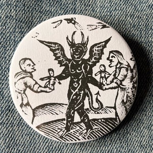 May include: A black and white illustration of a devil with wings and a tail, holding a doll. Two people are standing on either side of the devil, one holding a doll and the other holding a cross.