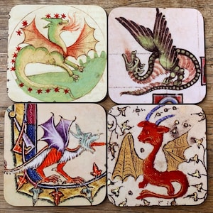 May include: Four square coasters featuring vintage illustrations of dragons. Each coaster depicts a different dragon with unique colours and designs. The dragons are depicted in a medieval style with intricate details.