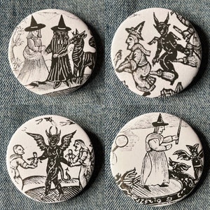 May include: Four black and white round buttons with images of witches and demons. The buttons are on a blue denim background.