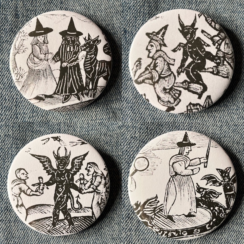 May include: Four black and white round buttons with images of witches and demons. The buttons are on a blue denim background.