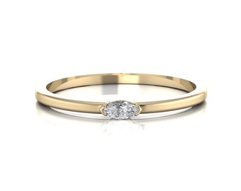 May include: A simple gold band ring with a single, small, oval-shaped diamond.