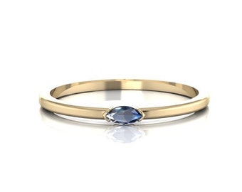 May include: A delicate gold band ring with a single marquise-shaped blue gemstone.