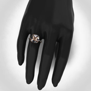 May include: A gold ring with a large, square-shaped, light brown gemstone surrounded by smaller, clear gemstones.