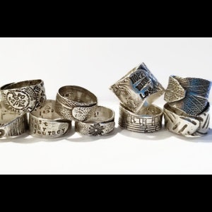 May include: A collection of eight silver rings with various designs and engravings. Some rings feature words like "Hope", "Love", and "Trust Your Journey".
