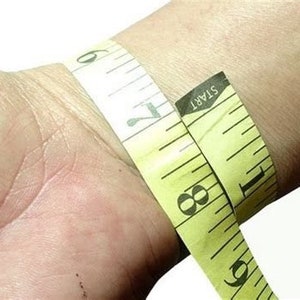 May include: A yellow measuring tape wrapped around a wrist, with the text "START" visible on the tape.
