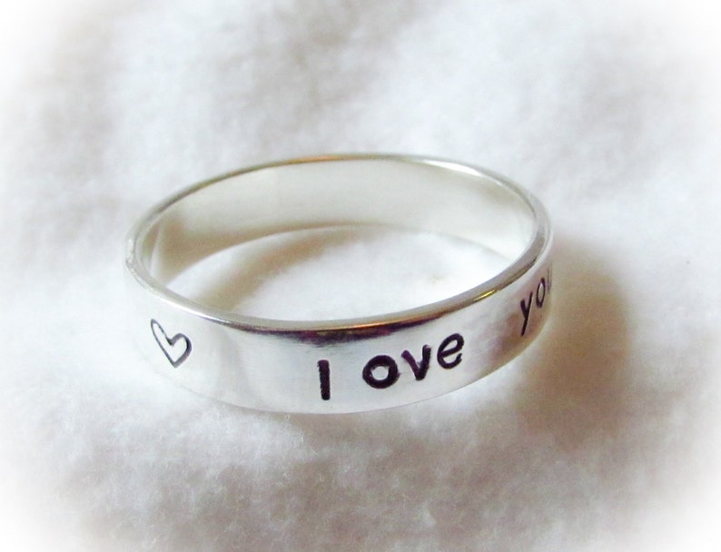 May include: A silver ring with the words "I love you" and a heart engraved on the band.