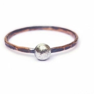 Puede incluir: Un anillo de plata simple con una banda de cobre martillada.