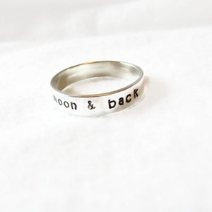 May include: A silver ring with the words "to the moon & back" engraved on the band.
