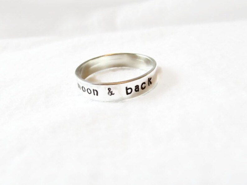 May include: A silver ring with the words "to the moon & back" engraved on the band.
