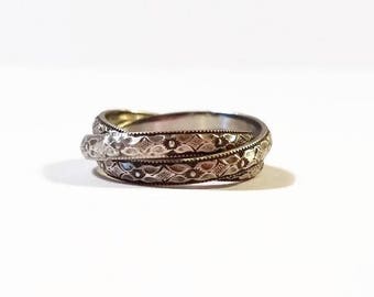 May include: A silver ring with a triple band design. Each band is intricately engraved with a floral pattern.