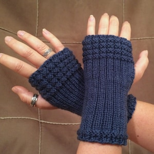May include: A pair of blue knitted fingerless gloves with a textured pattern. The gloves are shown on a person's hands.