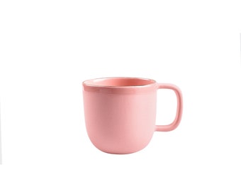 May include: A pink ceramic mug with a gold rim. The mug has a rounded shape and a handle.