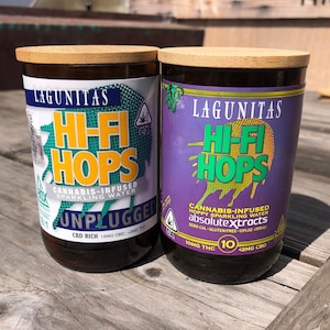 May include: Two glass bottles of Lagunitas Hi-Fi Hops cannabis-infused sparkling water. One bottle has a white and teal label with the word "Unplugged". The other has a purple label. Both have bamboo lids.